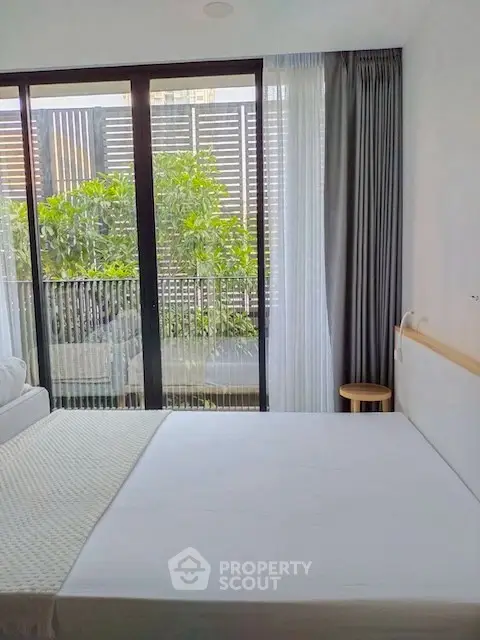 Modern bedroom with large window and garden view, featuring minimalist decor and cozy ambiance.