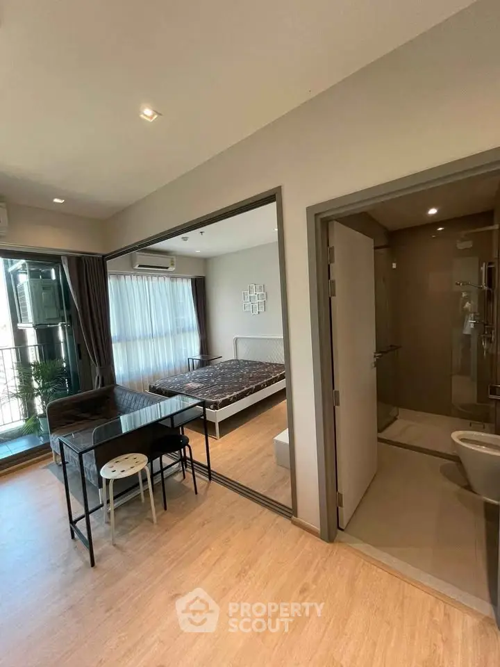 Modern studio apartment with open layout, featuring a cozy bedroom, compact dining area, and sleek bathroom.