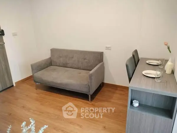 Cozy living room with modern sofa and dining table, perfect for small apartments.