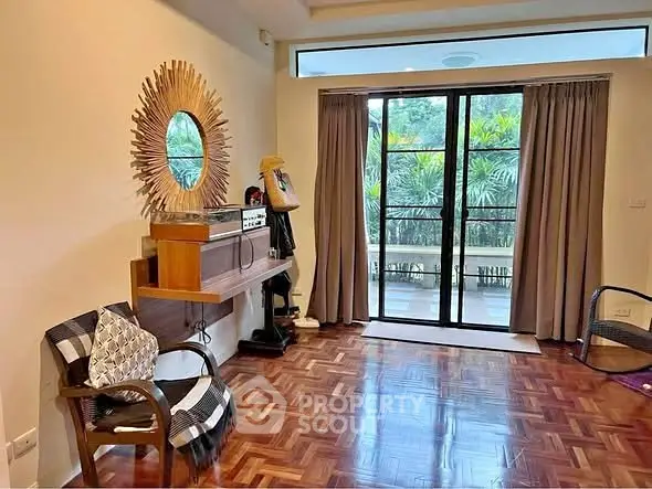 Charming living room with parquet flooring and stylish decor, featuring large windows opening to a lush garden view.