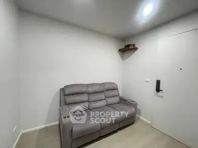 Cozy small living room with a comfortable gray sofa and modern lighting.