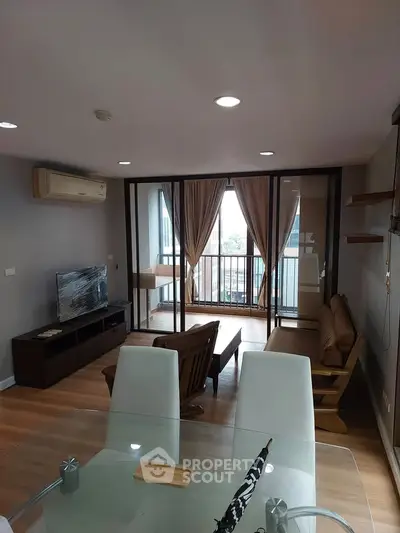 Modern living room with balcony view, stylish furniture, and ample natural light in a contemporary apartment.