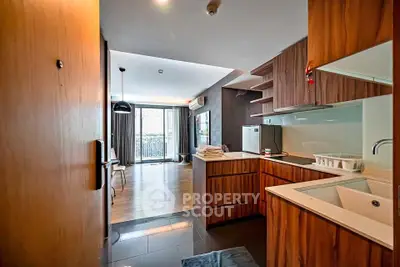 Modern open-layout kitchen and living room with wooden cabinetry and balcony view.