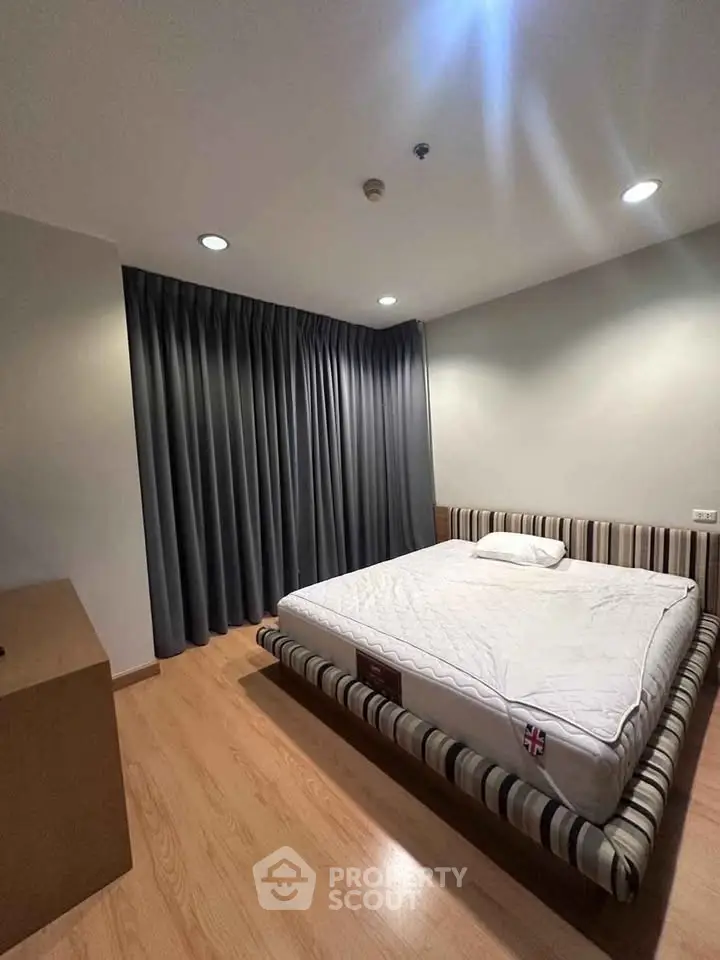 Spacious bedroom with modern design and cozy ambiance, featuring a stylish bed and elegant wooden flooring.