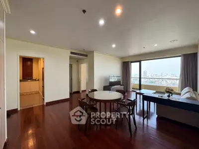 Spacious living room with wooden flooring and city view from large windows.
