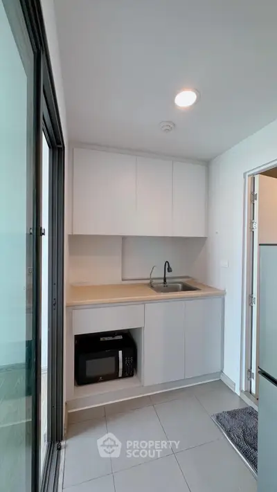 Modern compact kitchen with sleek cabinetry and built-in microwave, perfect for urban living.