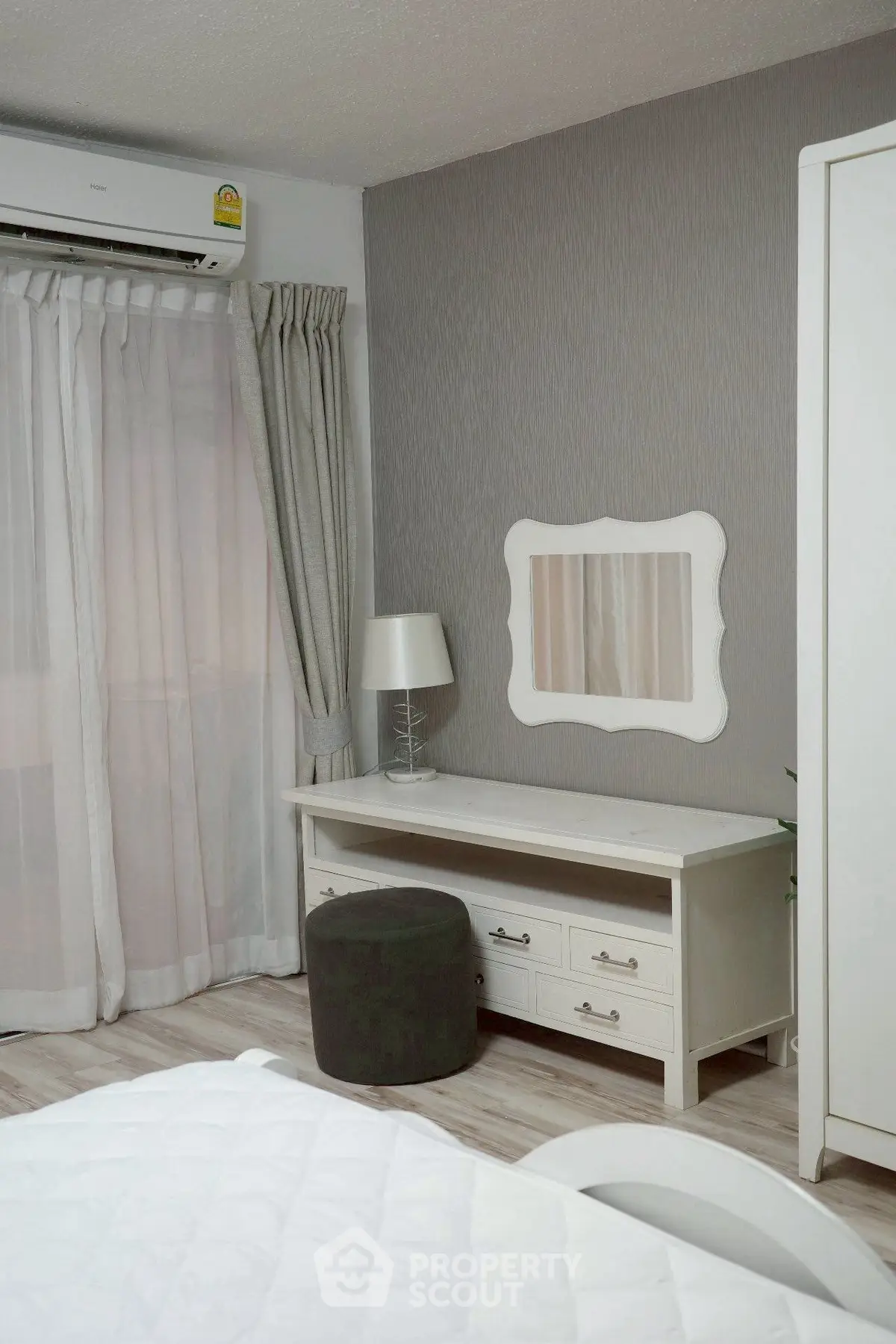 Charming bedroom with elegant decor and natural light, featuring a stylish vanity and cozy ambiance.