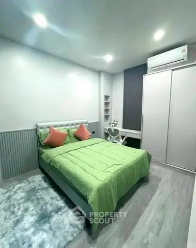 Modern bedroom with green bedding, sleek design, and air conditioning unit.