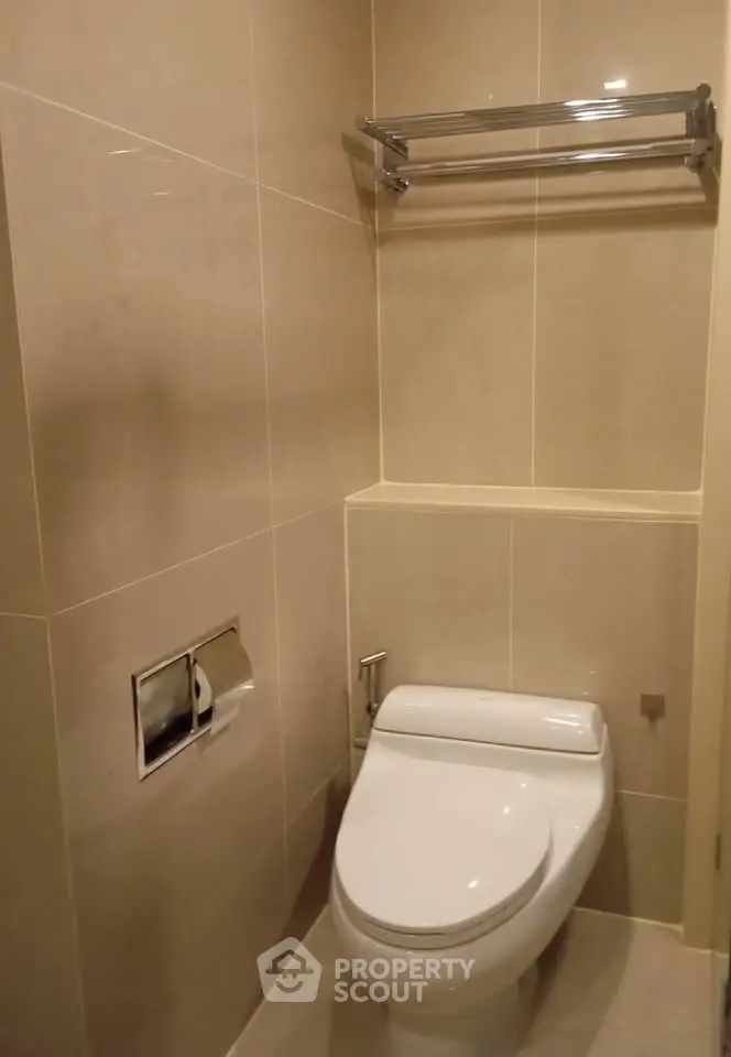 Modern bathroom with sleek toilet and towel rack in minimalist design.