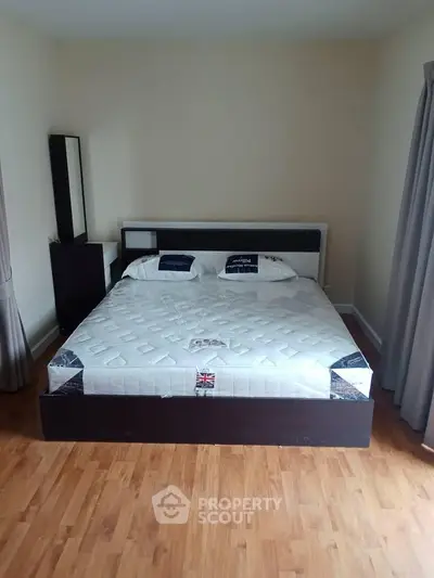 Spacious bedroom with a large bed and wooden flooring, perfect for comfort and relaxation.