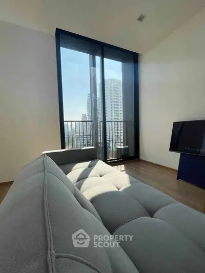 Modern living room with large windows offering stunning city views and stylish furniture.