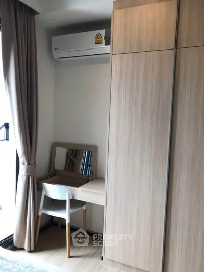 Cozy study nook with wooden desk and chair, complemented by a sleek wardrobe and air conditioning unit.