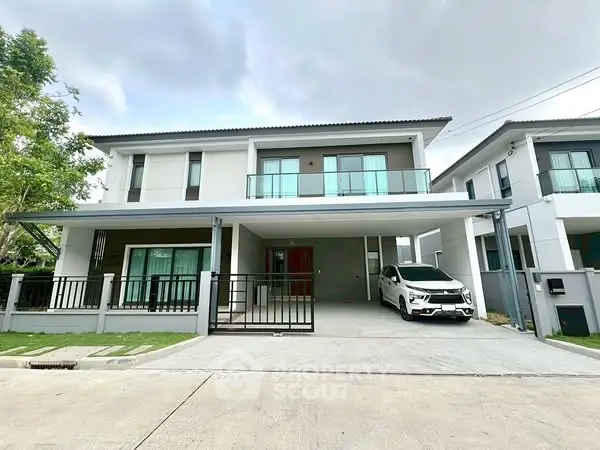 Modern two-story house with carport and sleek balcony design.