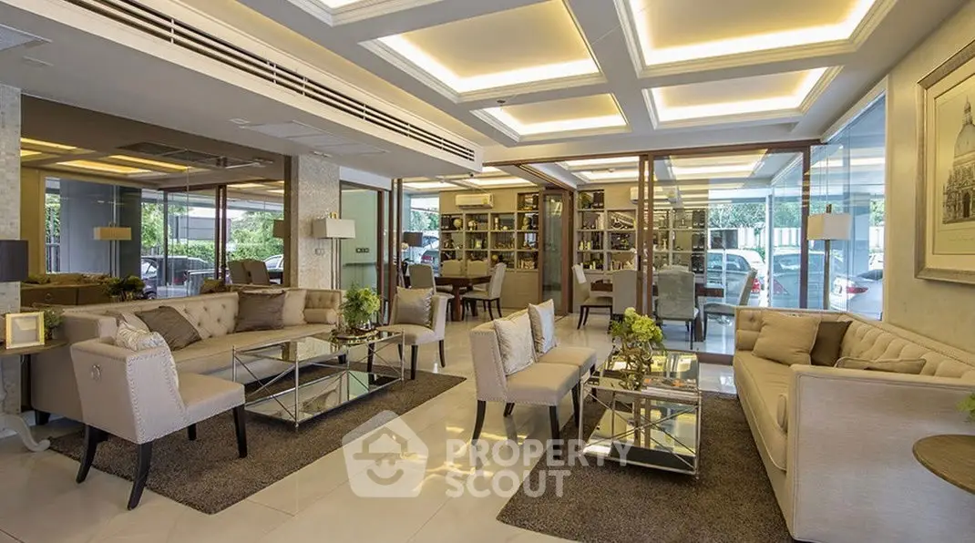 Luxurious modern living room with elegant furniture and large windows offering a garden view.