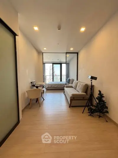 Modern studio apartment with open layout and cozy decor, featuring a comfortable sofa and a small Christmas tree.