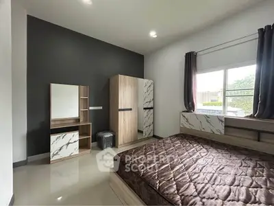 Modern bedroom with sleek furniture and large window offering natural light.