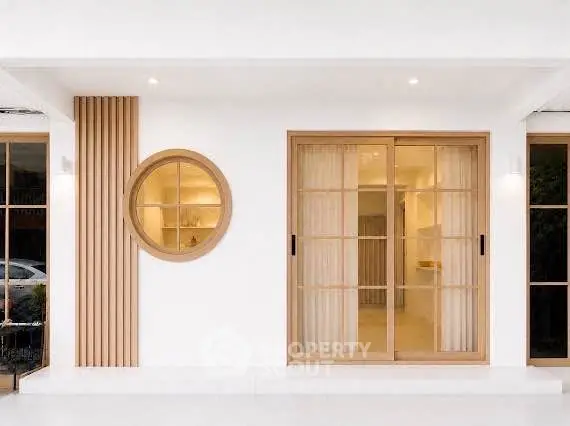 Modern minimalist exterior with circular window and sliding glass doors.