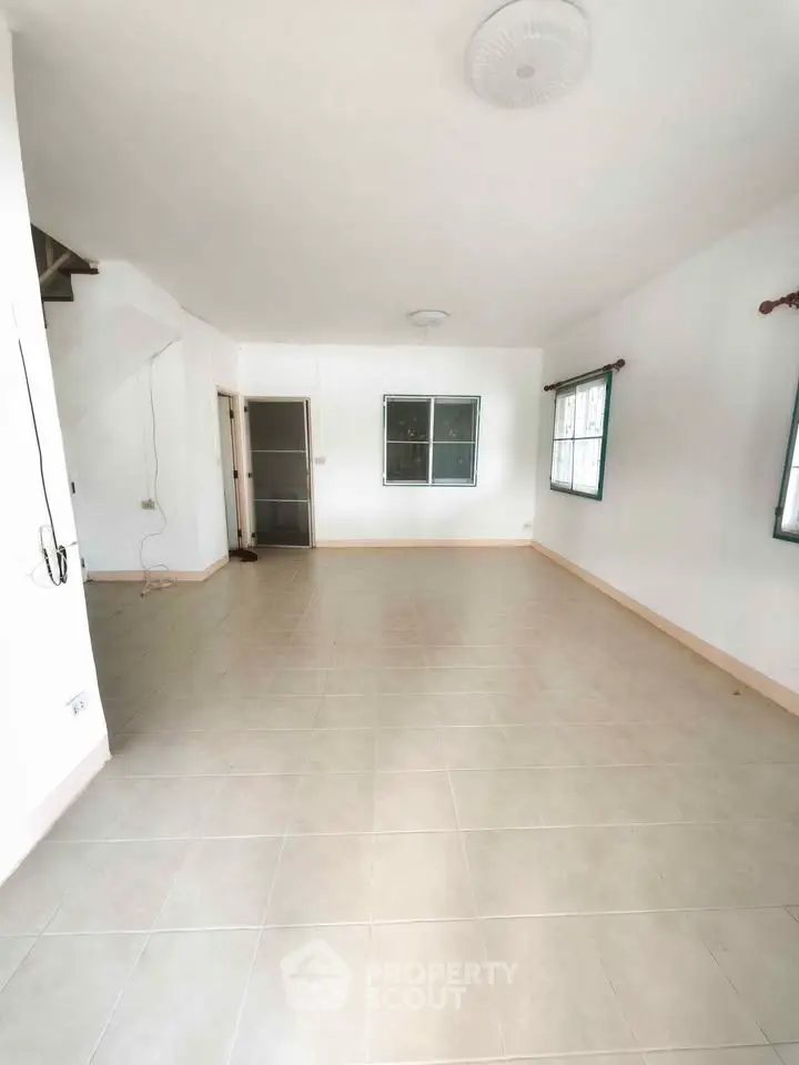 Spacious empty living room with tiled flooring and large windows, perfect for customization.
