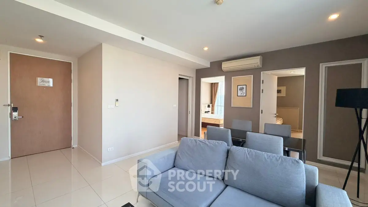 Modern living room with gray sofa and dining area in open layout apartment.