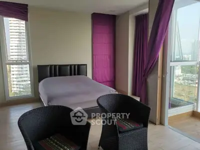 Spacious bedroom with large windows and city view, featuring modern decor and comfortable seating area.