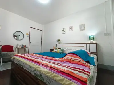 Cozy bedroom with colorful bedding and minimalist decor, perfect for relaxation.