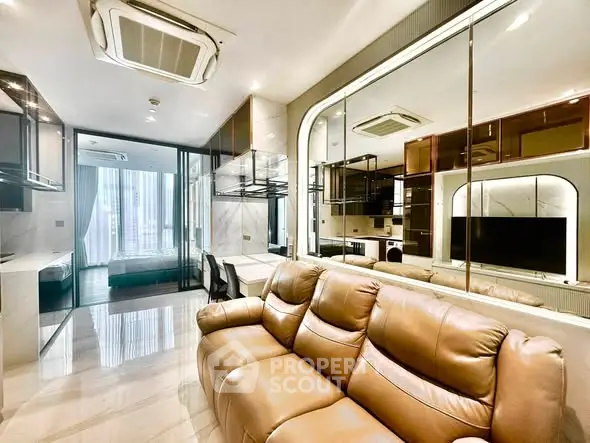 Luxurious modern living room with leather sofa and mirrored walls, leading to a stylish bedroom.