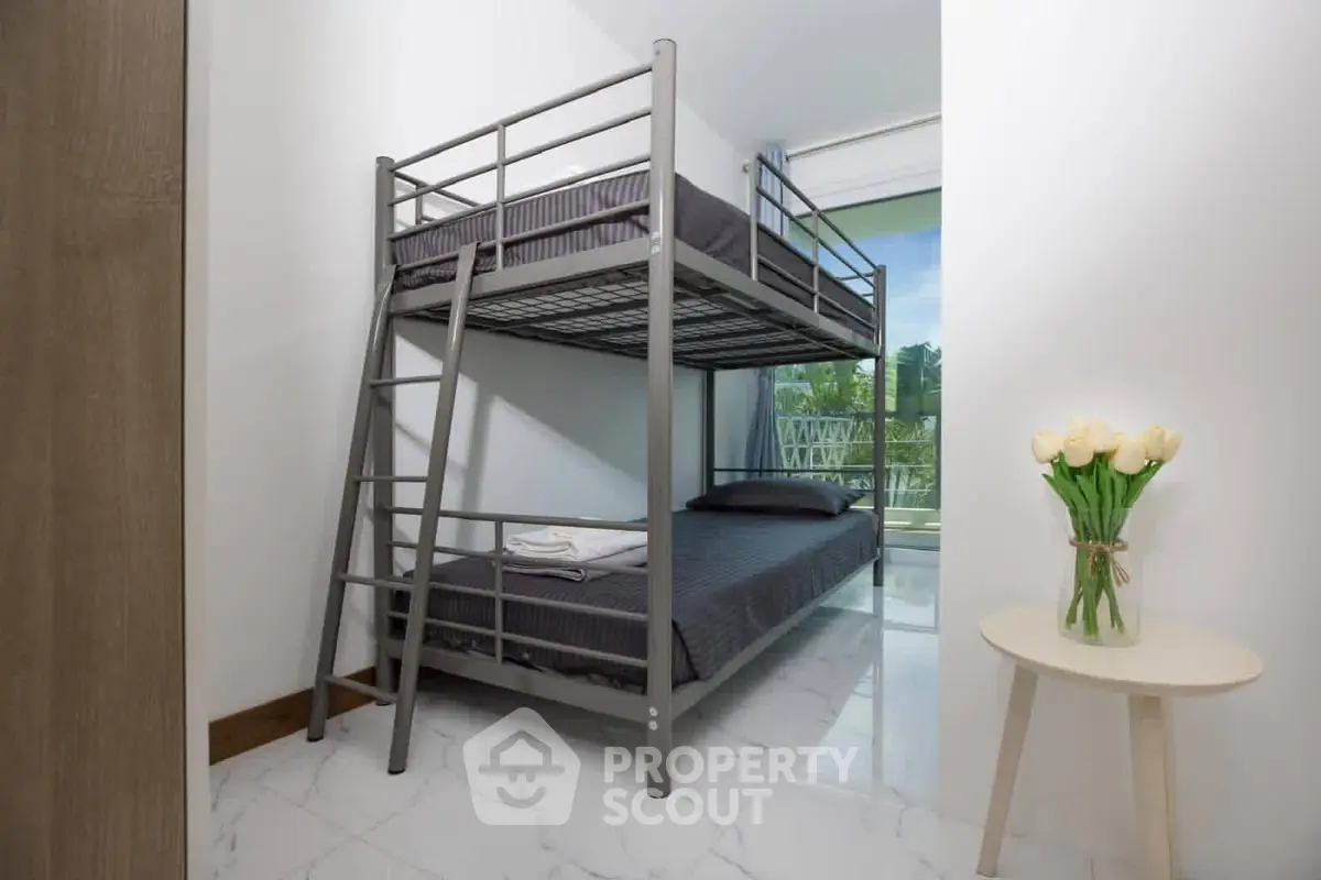 Modern bedroom with bunk bed and balcony view, featuring sleek design and natural light.