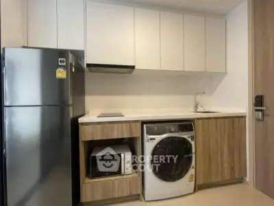 Modern kitchen with sleek appliances including fridge, microwave, and washing machine in compact layout.