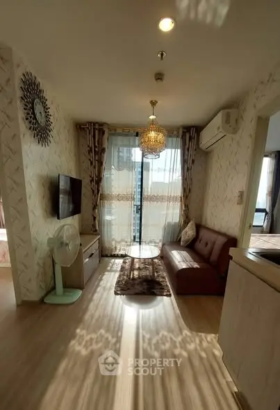 Charming living room with elegant decor, chandelier, and natural light in modern apartment.