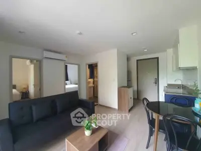 Modern open-plan living room with sleek black sofa and compact kitchen area, perfect for urban living.