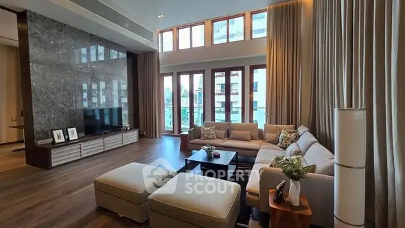 Luxurious living room with high ceilings and large windows offering stunning city views.