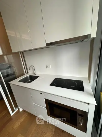 Modern compact kitchen with sleek white cabinets and built-in appliances