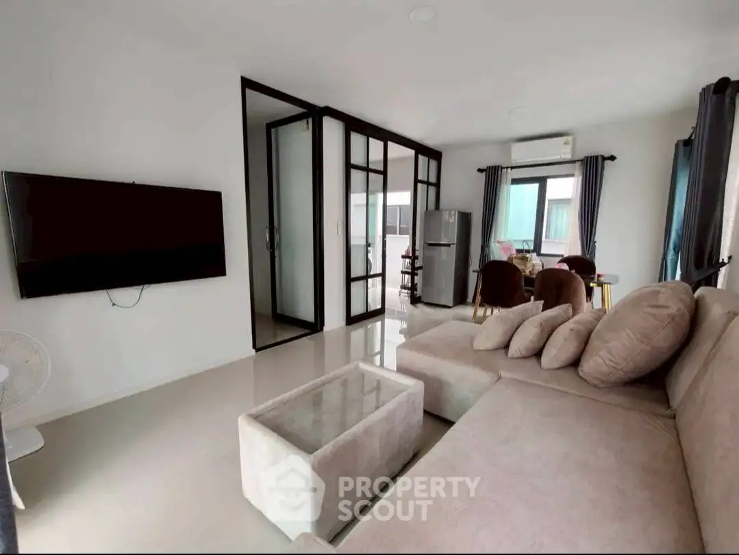 Modern living room with sleek design, featuring a cozy sectional sofa and wall-mounted TV, perfect for relaxation.