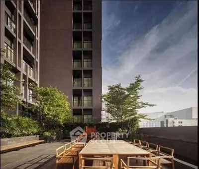 Modern building exterior with spacious outdoor seating area and lush greenery.