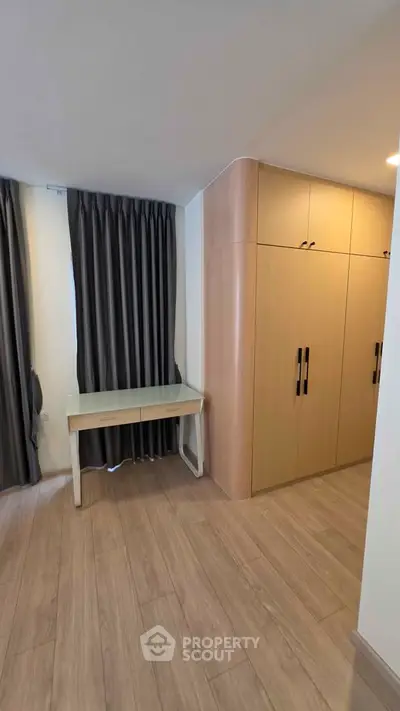 Modern bedroom with sleek wooden wardrobe and stylish desk, perfect for urban living.