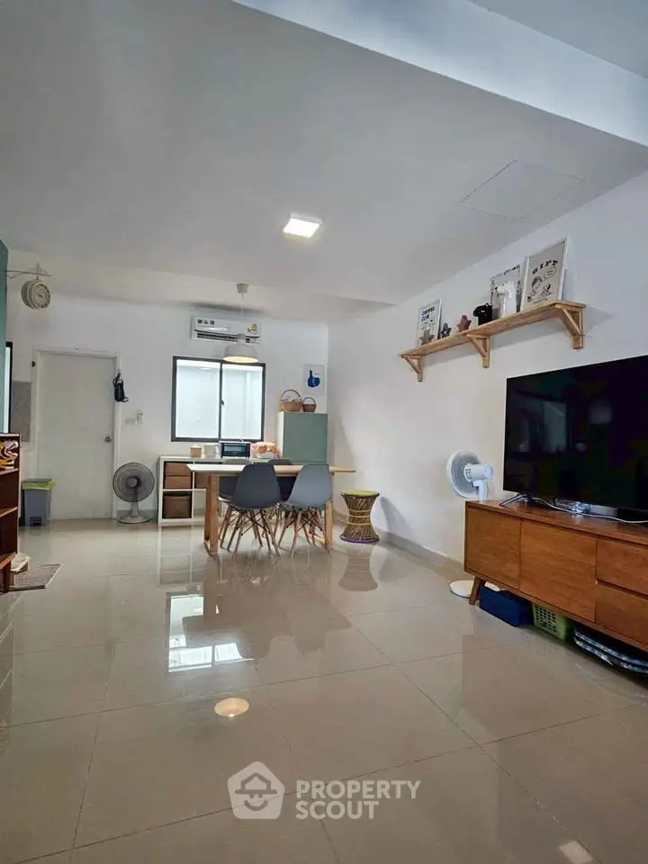 Spacious living room with modern decor and large TV, perfect for relaxation and entertainment.