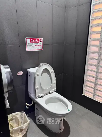Modern bathroom with sleek design and natural light, featuring a contemporary toilet and stylish wall tiles.