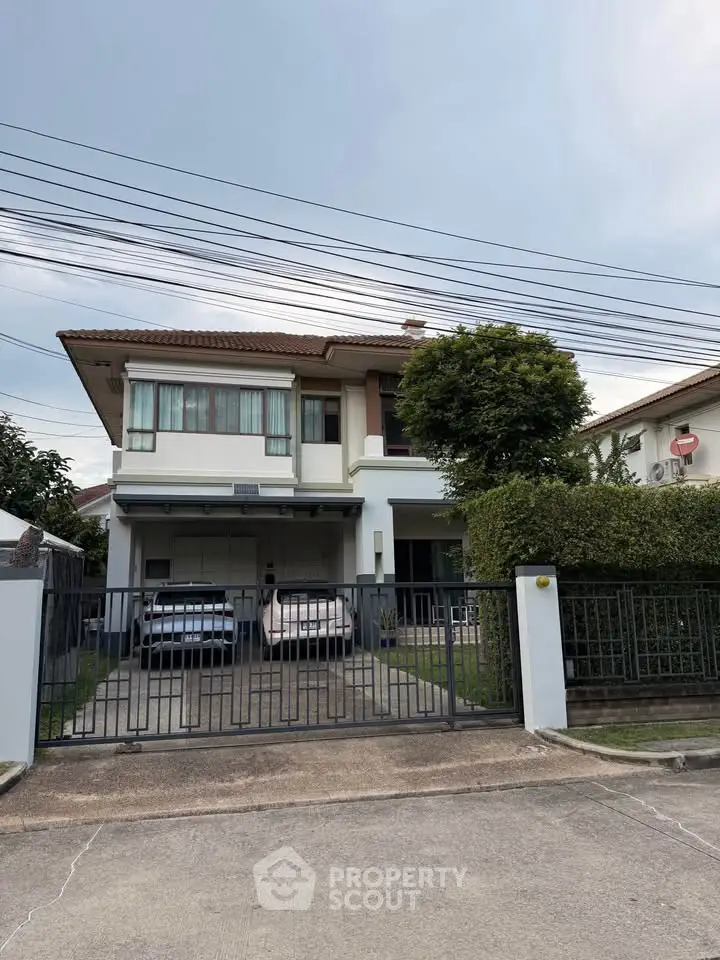 Charming two-story house with spacious driveway and lush greenery in a serene neighborhood.