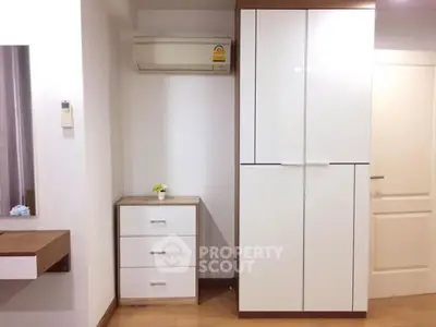 Modern bedroom with sleek white wardrobe and air conditioning unit