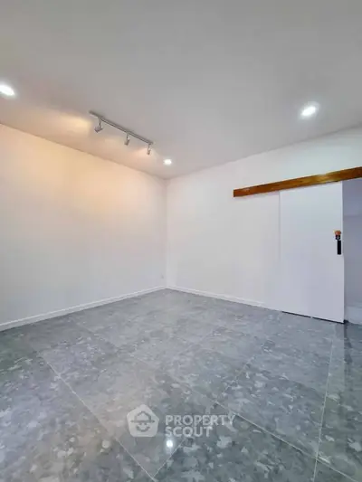 Spacious empty room with modern tile flooring and sliding door