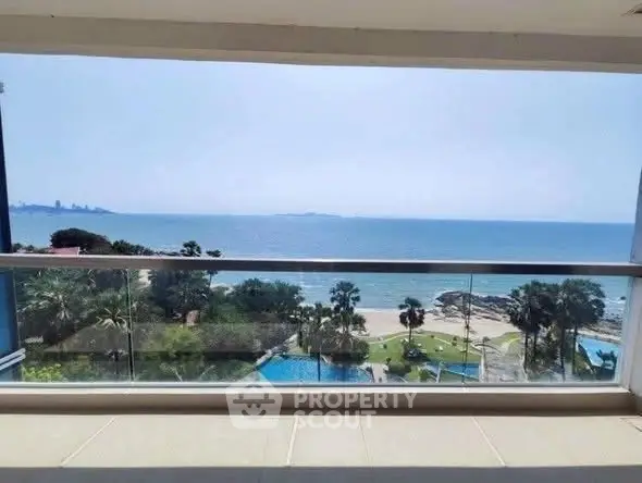 Stunning ocean view from a high-rise balcony overlooking a pristine beach and lush greenery.