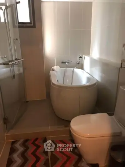 Modern bathroom with sleek design featuring a bathtub and glass shower enclosure.