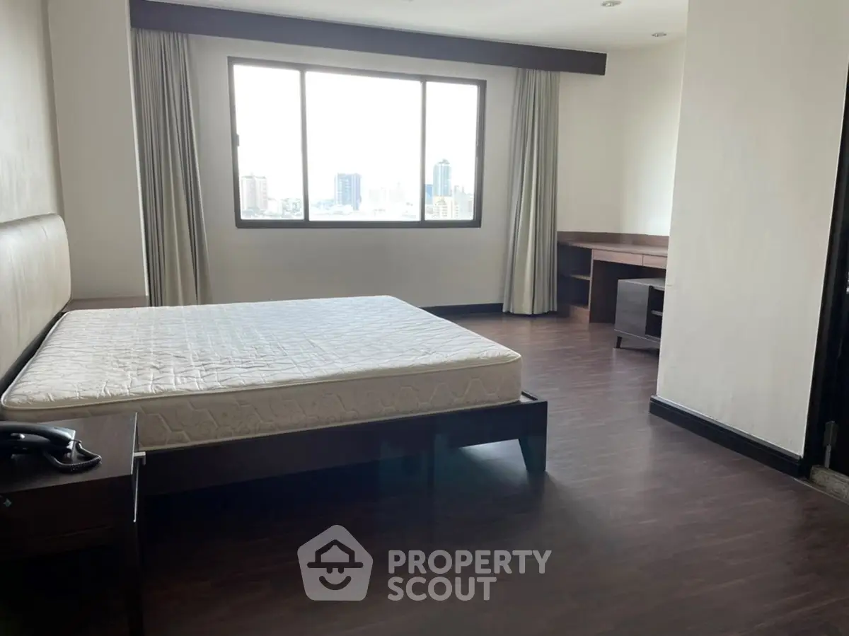 Spacious bedroom with city view and elegant wooden flooring