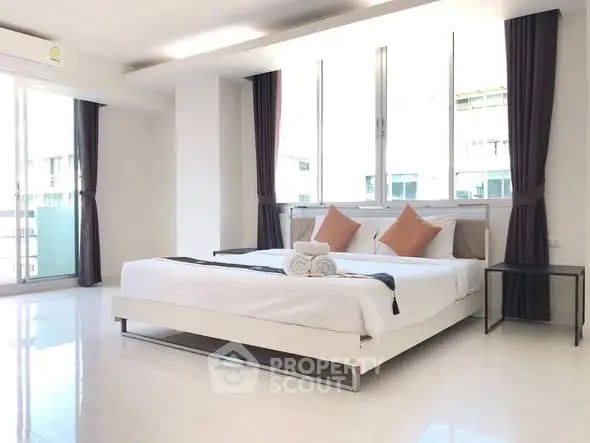Spacious modern bedroom with large windows and elegant decor in a luxury apartment.
