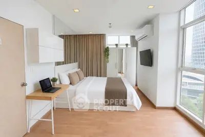 Modern bedroom with large windows and city view, featuring minimalist decor and natural light.