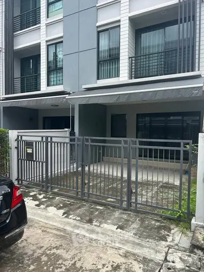 Modern townhouse exterior with gated entrance and sleek design.