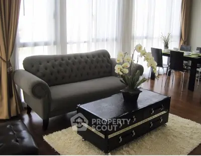 Elegant living room with plush sofa and chic dining area, featuring floor-to-ceiling windows and stylish decor.