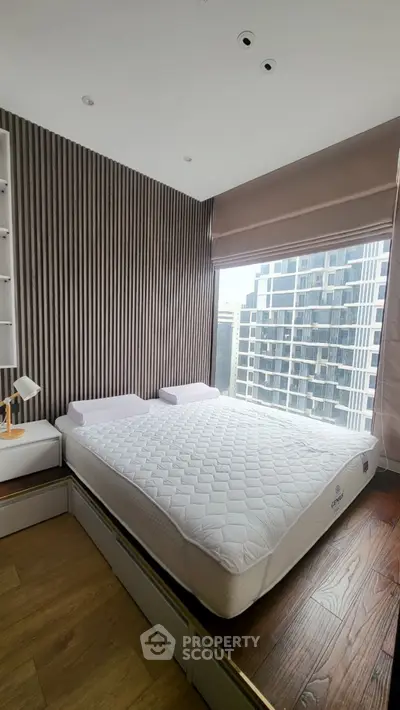 Modern bedroom with large window and city view, featuring stylish wood paneling and a comfortable bed.