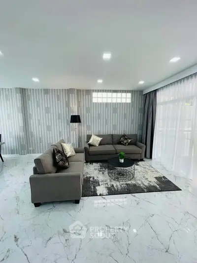 Elegant living room with modern gray sofas, stylish wallpaper, and marble flooring.