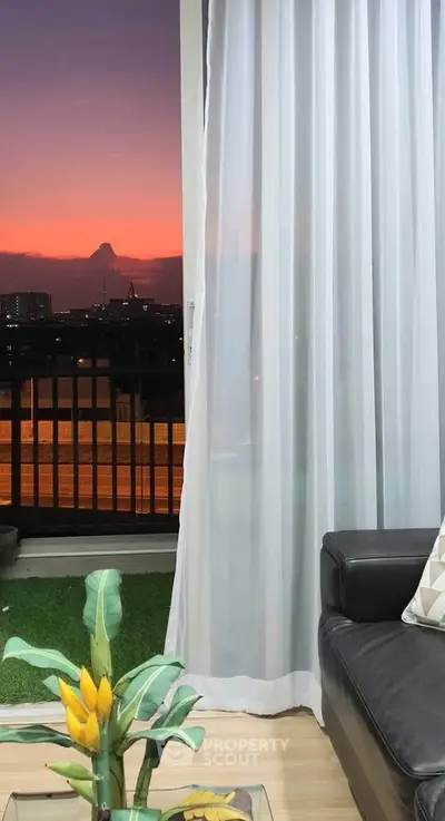 Chic living room with stunning sunset view from balcony, featuring modern decor and cozy ambiance.